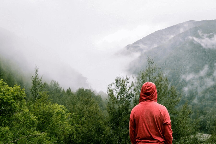 muž v červené mikině stojí na horách v dešti. Zdroj: https://www.pexels.com/cs-cz/foto/395242/